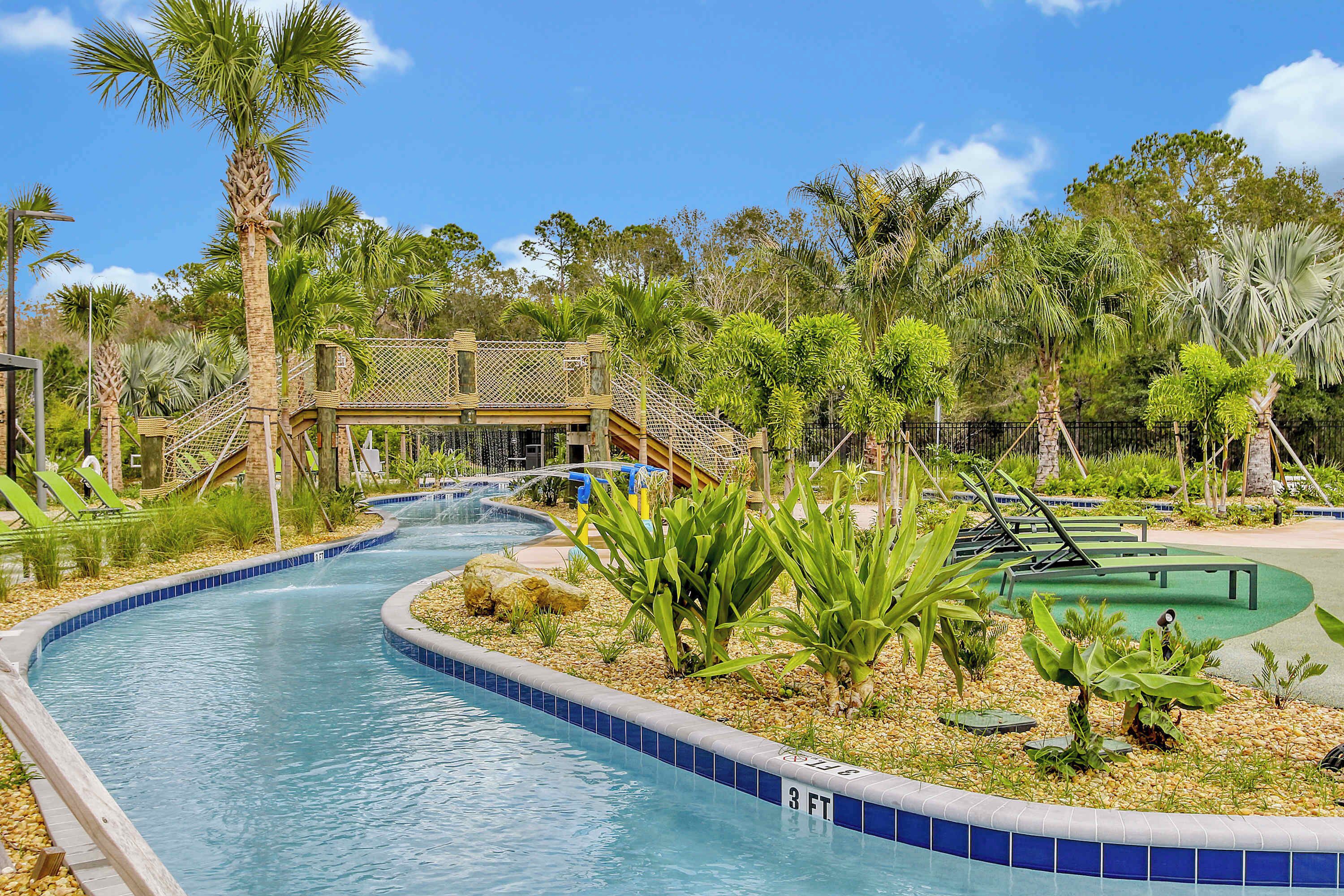 A pool area with a water slide, palm trees, and a wooden deck.
