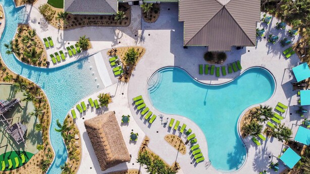 An aerial view of a resort with a large central pool, multiple smaller pools, and sun loungers arranged around the pools. - 7 miles to Disney, private pool + lazy river (Kissimmee)