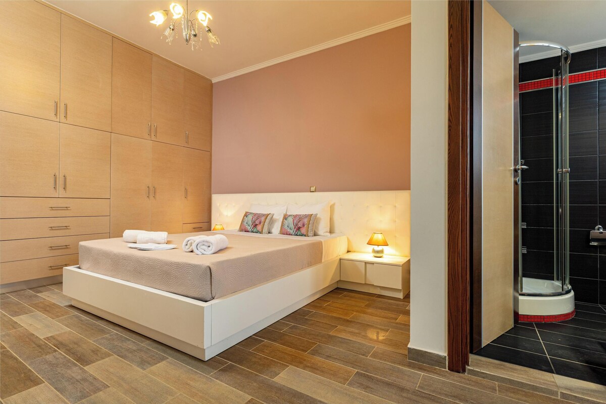 Ein Schlafzimmer mit Bett, Nachttischen, einem Kleiderschrank und einer Duschkabine.
