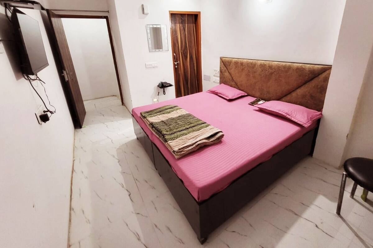 Une chambre à coucher avec un lit, une chaise, une télévision, un miroir et une porte.
