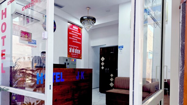 Una reception hotel con un cartello che riporta 'HOTEL JK', un lampadario, un'area accoglienza e un divano rosso.