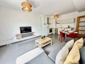 Ein modernes Wohnzimmer mit Sofa, Fernseher und Essbereich.