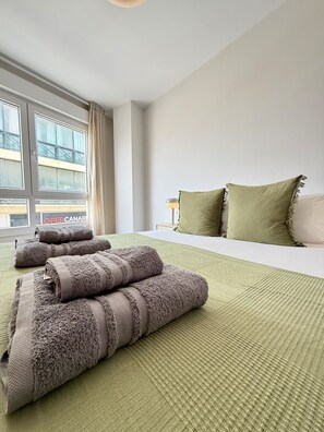 Ein Hotelzimmer mit einem großen Bett, einem Fenster mit Vorhängen und Blick auf ein Gebäude.