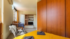 A hotel room with a bed, a chair, a desk with a computer, and a wardrobe. - Accommodation with Private Parking - Cagliari (Cagliari)
