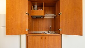 A compact kitchen with a built-in sink, a small countertop, and a cabinet with a hinged door. - Accommodation with Private Parking - Cagliari (Cagliari)