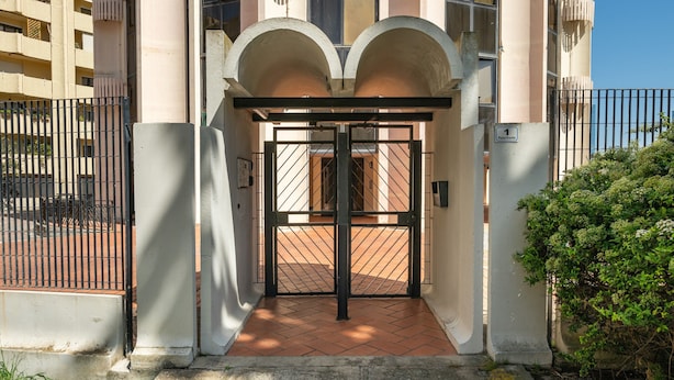 A building entrance with a gated entrance, a tiled floor, and a clear sky. - Accommodation with Private Parking - Cagliari (Cagliari)