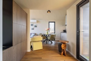 A modern interior with a dining area, a sofa, and a trash bin.