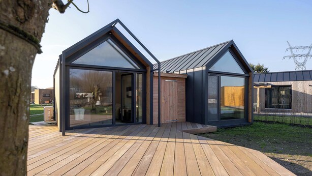 Una casa moderna con ampie finestre in vetro e un terrazzo in legno.