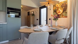 Un comedor con una mesa de madera, sillas grises y una lámpara de techo moderna.