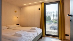Ett modernt hotellrum med en stor säng, en skjutdörr till en balkong och en väggmonterad lampa.