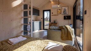 Una habitación con cama, silla, escalera, lavabo y televisor.