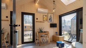 Un interior moderno con paredes de madera, zona de comedor, televisor y vistas al exterior.