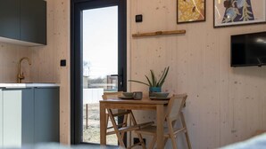 Una cocina moderna con una mesa y sillas de madera, un televisor montado en la pared y una puerta que da al exterior.