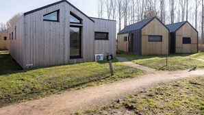 A modern building with a sloped roof, large windows, and a sign indicating the number 27. - Tiny House with forest view in Oud Ade | Tuin van Keet - 27 (Oud Ade)