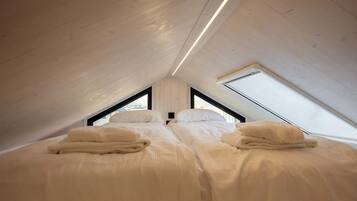 Une chambre avec deux lits, une lucarne et un plafond en bois.