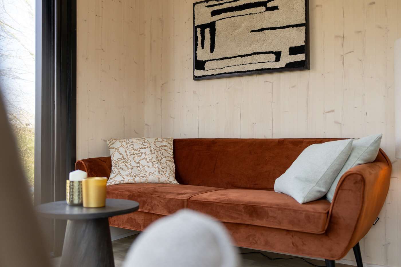 Ein Zimmer mit einer braunen Couch, einem runden Tisch und einem Fenster.