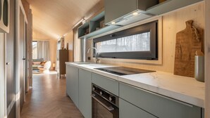 Une cuisine moderne dotée d’une grande fenêtre, d’appareils électroménagers intégrés et d’un parquet en bois disposé en chevrons.