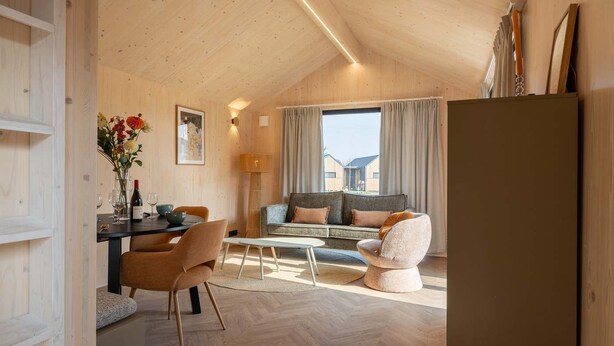 Une pièce chaleureuse avec un plafond en bois, un canapé, une table à manger et une grande fenêtre.