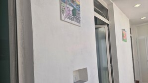 Un pasillo con paredes blancas, una puerta y un ventanal.