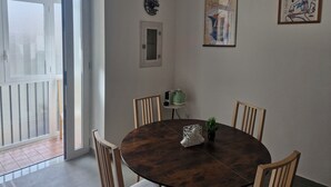Un comedor con una mesa redonda, cuatro sillas, una planta en maceta y dos cuadros en la pared.