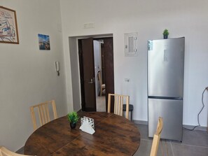 A dining area with a round wooden table, chairs, a small potted plant, and a refrigerator. - Franceschina Just renovated, downtown. (Napoli)