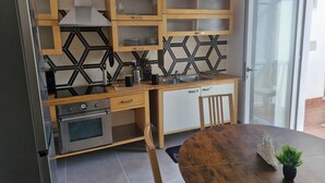 Una cocina moderna con horno empotrado, pileta de acero inoxidable, armarios de madera y una mesa de comedor redonda.