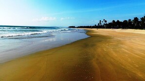Una spiaggia con un'ampia riva sabbiosa, onde oceaniche e cielo sereno.
