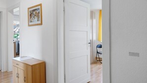 A hallway with a white door, a wooden cabinet, and a framed picture on the wall.