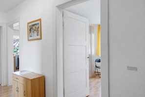 Ein Flur mit einer weißen Tür, einem Holzschrank und einem gerahmten Bild an der Wand.
