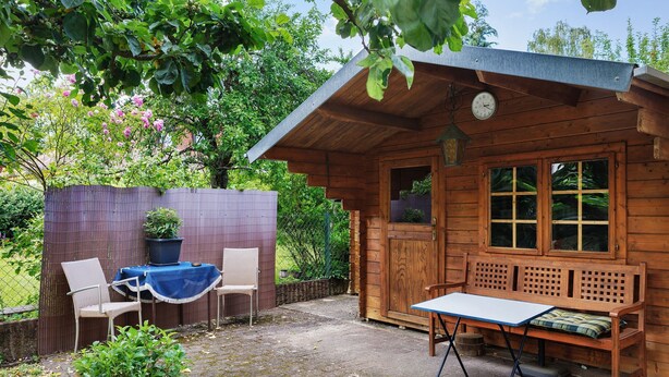 A wooden cabin with a bench, a table, and two chairs.