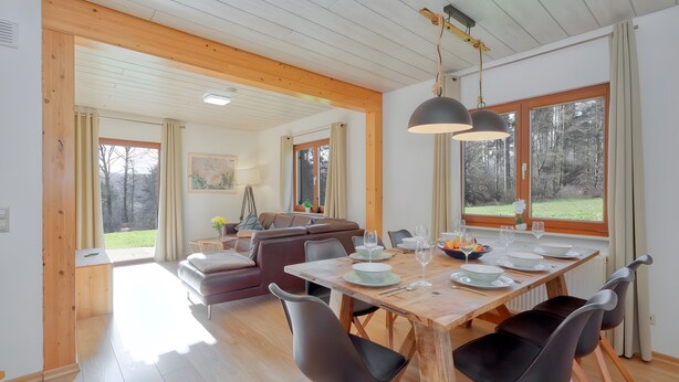 Un espace repas avec une table en bois, des chaises et une vue sur l’extérieur.