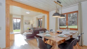 Un espace repas avec une table en bois, des chaises et une vue sur l’extérieur.