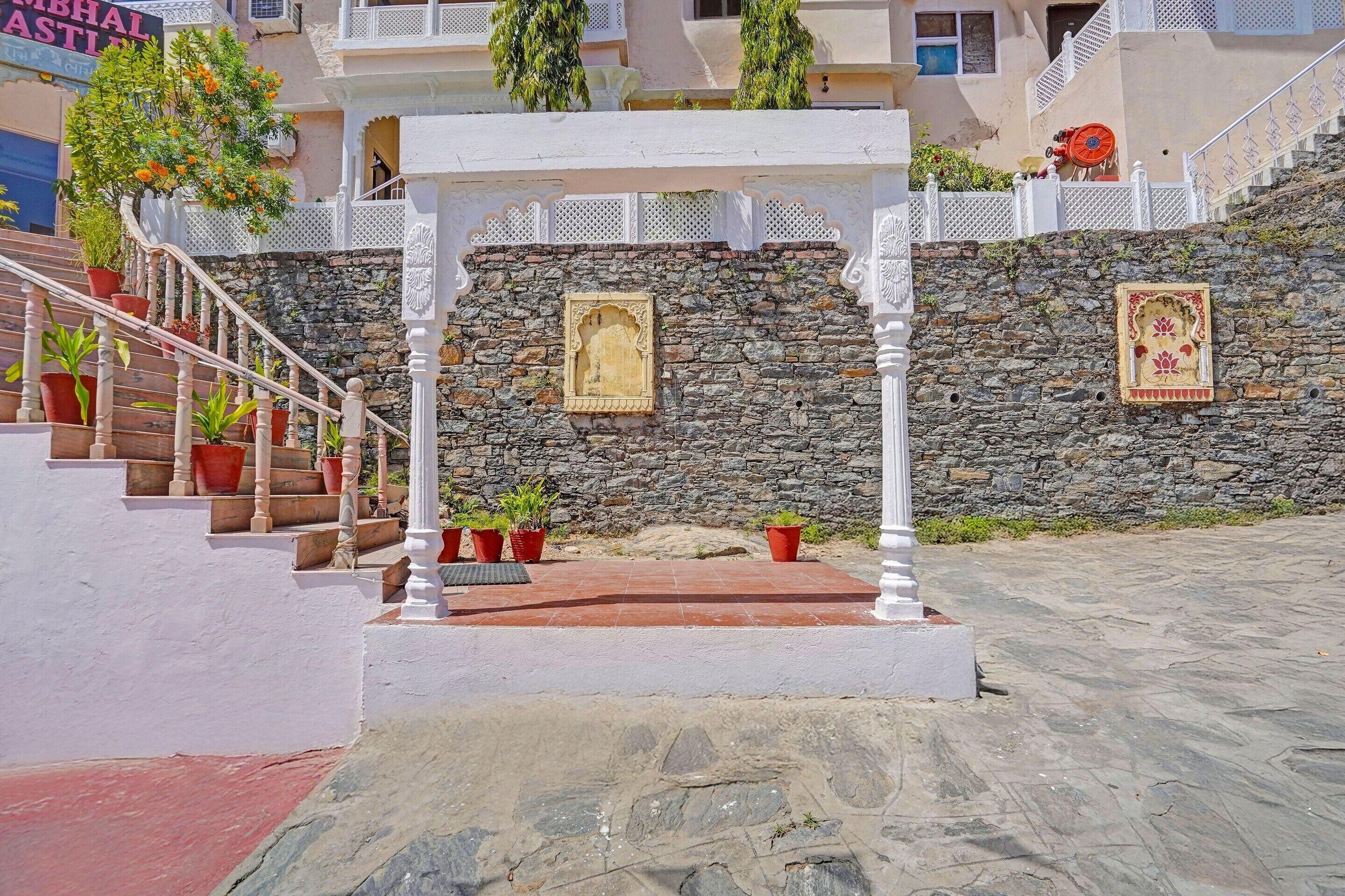 A stone wall with a white railing, a stone staircase, and a small shrine with a framed picture.