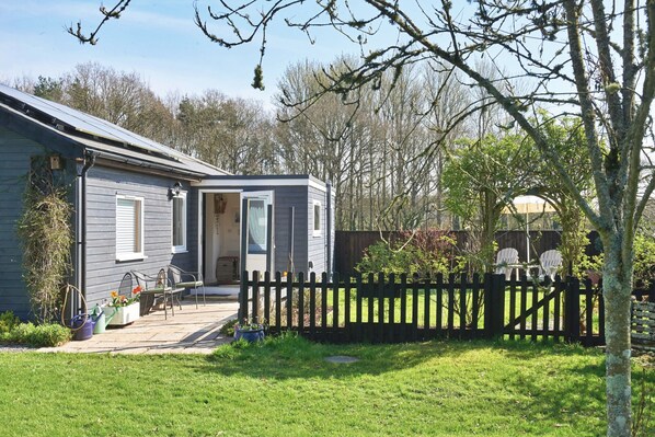 Une maison avec un patio, une clôture et un jardin.