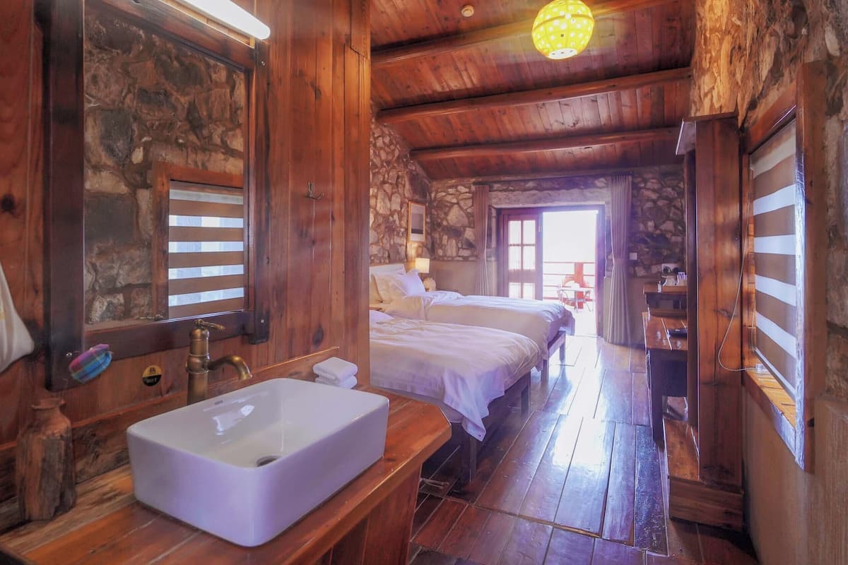 L’intérieur d’un chalet en bois comprend une salle de bain, un lit et un mur en pierre.