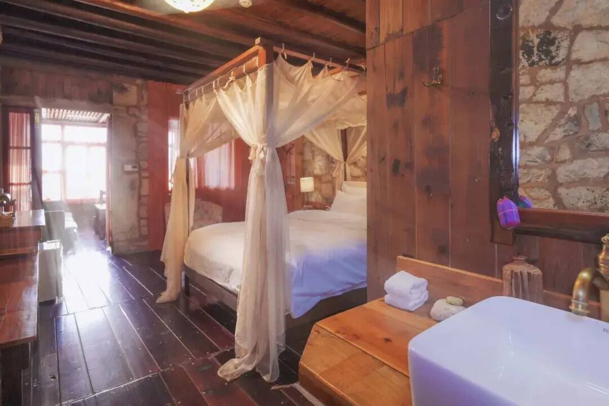 Une pièce en bois avec un lit, un banc en bois, un mur en pierre et un lavabo.