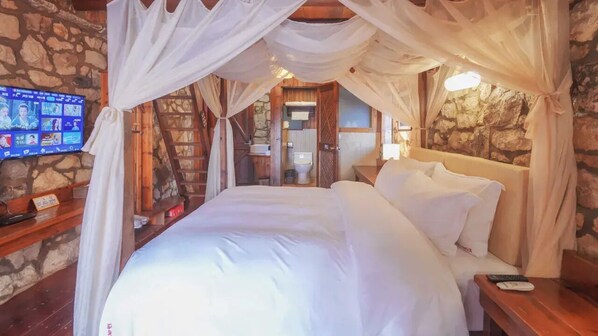 Ein Schlafzimmer mit Bett, Fernseher und einer Steinwand.
