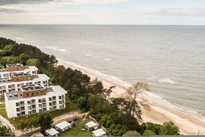 Un hotel costero con edificios de varios pisos, una playa y vistas al mar.