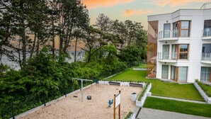 En modern byggnad med en takträdgård, en gunga och en sandlåda.