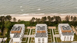 Ett hotell vid kusten med modern arkitektur, utsikt över stranden och en vackert anlagd trädgård.