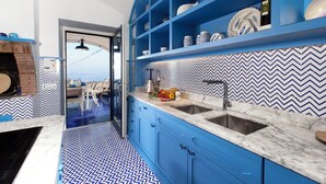 A modern kitchen with blue cabinetry, a marble countertop, and a herringbone-patterned backsplash. - De Vivo Realty - Villa Blue Skyline (Marciano)
