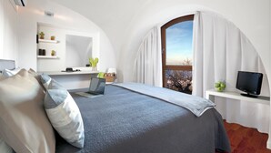 Ein Schlafzimmer mit Bett, Laptop, Fernseher, einem Fenster mit Vorhängen, einem Regal mit Pflanzen und einer weißen Wand.