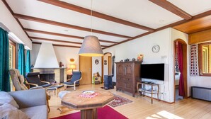Una sala de estar con sofá, sillas, una mesa, televisor y chimenea.