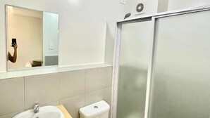 Ein modernes Badezimmer mit Waschbecken, Toilette und einer Duschkabine aus Glas.