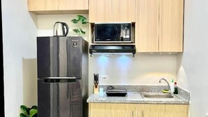 Eine kleine Küche mit Kühlschrank, Mikrowelle und einer Arbeitsplatte aus Granit.