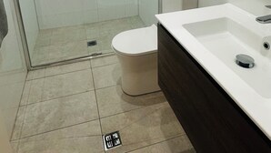 A modern bathroom with a glass-enclosed shower, a white toilet, and a white sink with a dark countertop. - Modern Studio Sydney (108) - 2 km to Sydney University (Stanmore)