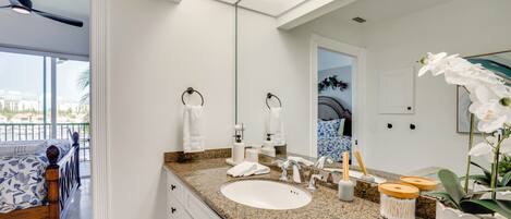 A modern bathroom with a large mirror, white sink, and a ceiling fan.