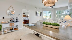 Uma cozinha moderna com bancada de madeira, luminária pendente e vista para a sala de estar.