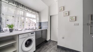 Een moderne keuken met een wasmachine, een spoelbak en een raam met gordijnen.