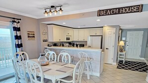 Ein Strandhaus-Interieur mit Essbereich, Küche und einem Balkon mit Meerblick.